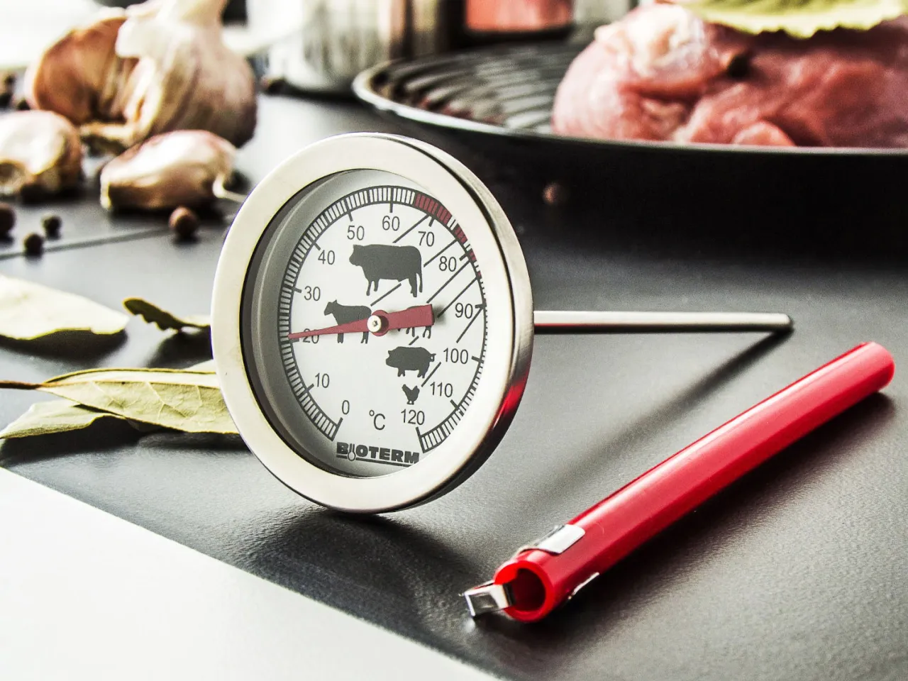 Termometr kuchenny i surowa wieprzowina na patelni. Sprawdź, ile gotować wieprzowinę, by była idealna.