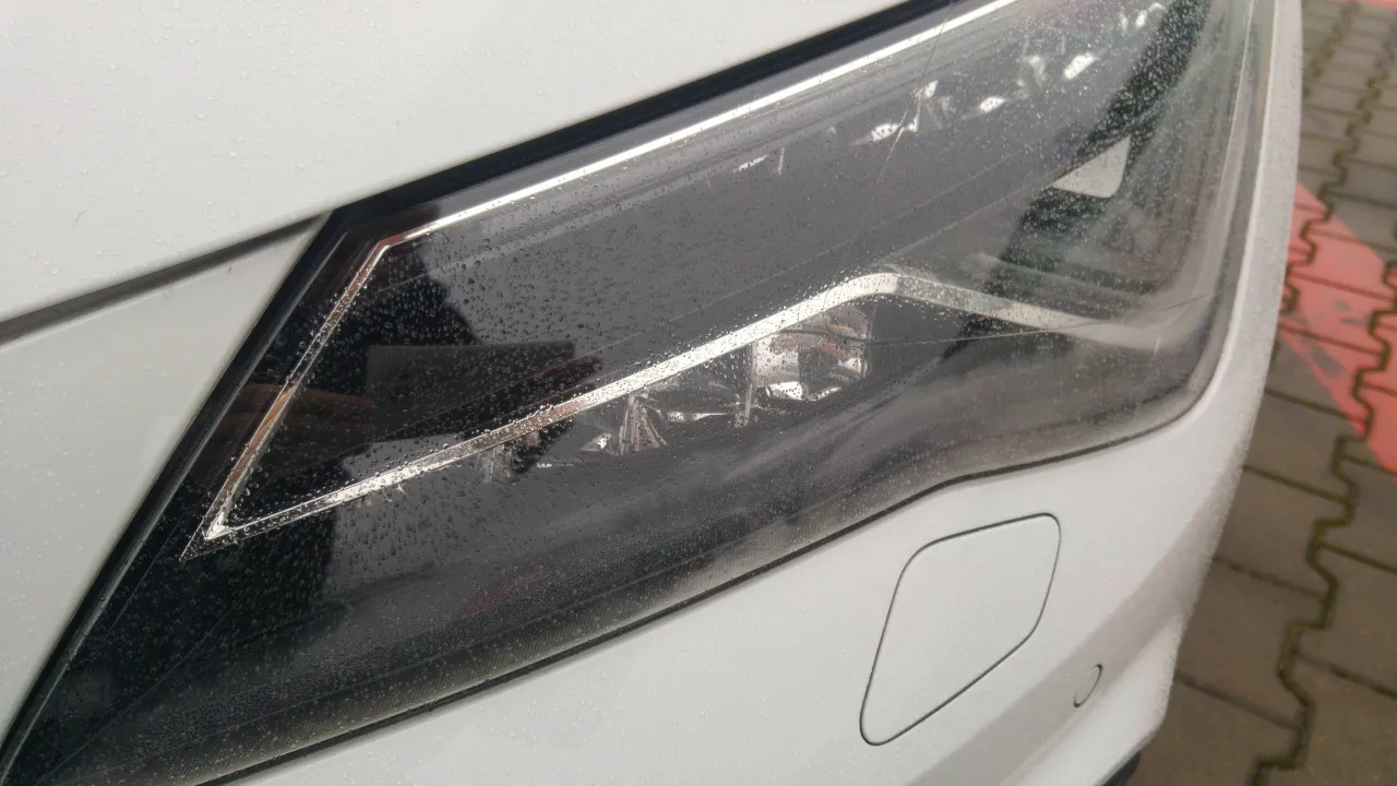 Krople deszczu na parujących reflektorach LED w nowym aucie.