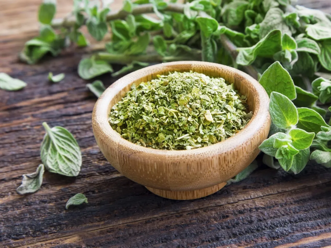 Suszone i świeże oregano, idealne zioła do pizzy, w drewnianej miseczce na rustykalnym tle.