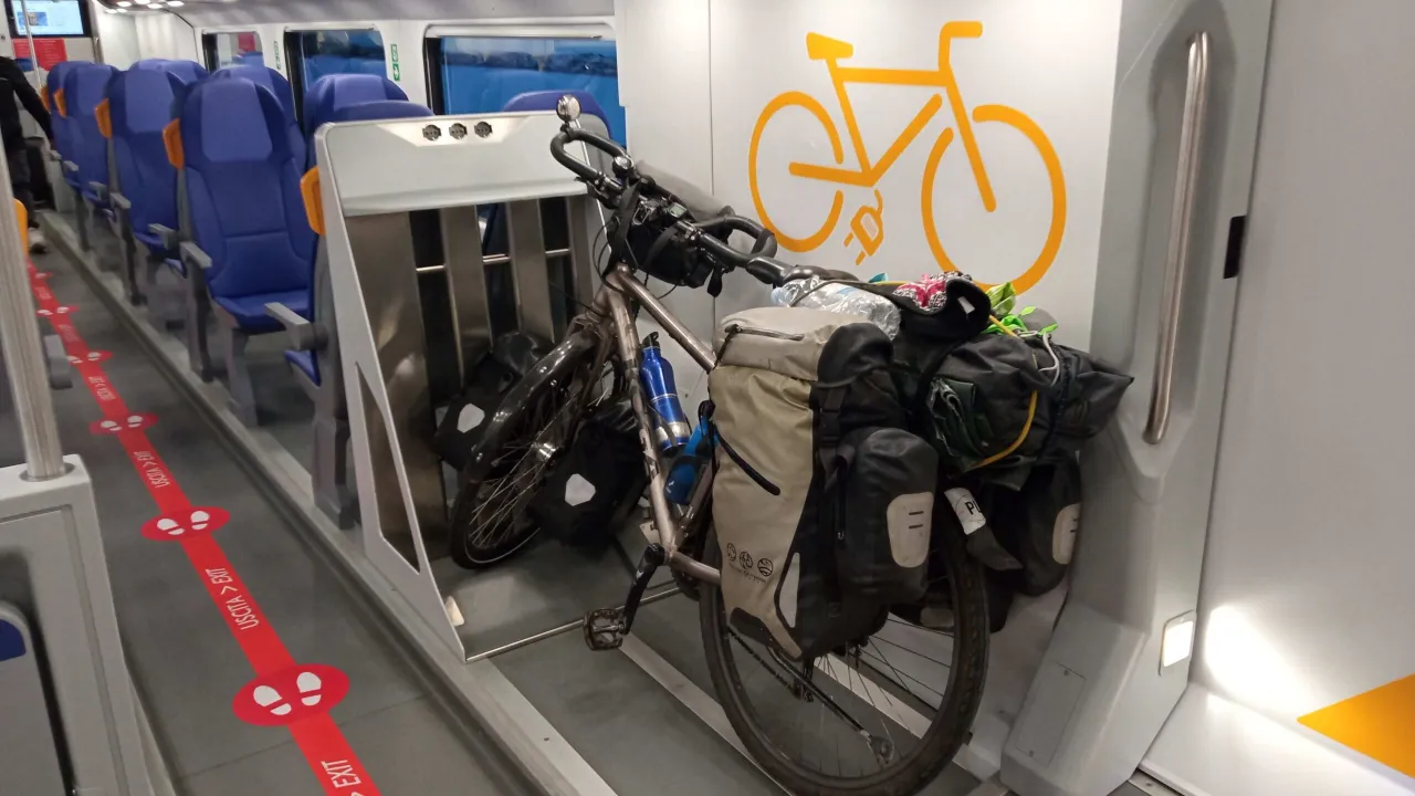 Rower z sakwami gotowy do podróży pociągiem. Widać miejsce do jego transportu, oznaczone symbolem roweru.