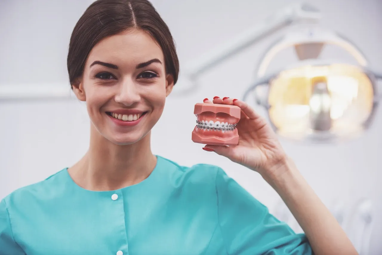 osoba z aparatem ortodontycznym przykładająca zimny okład do policzka