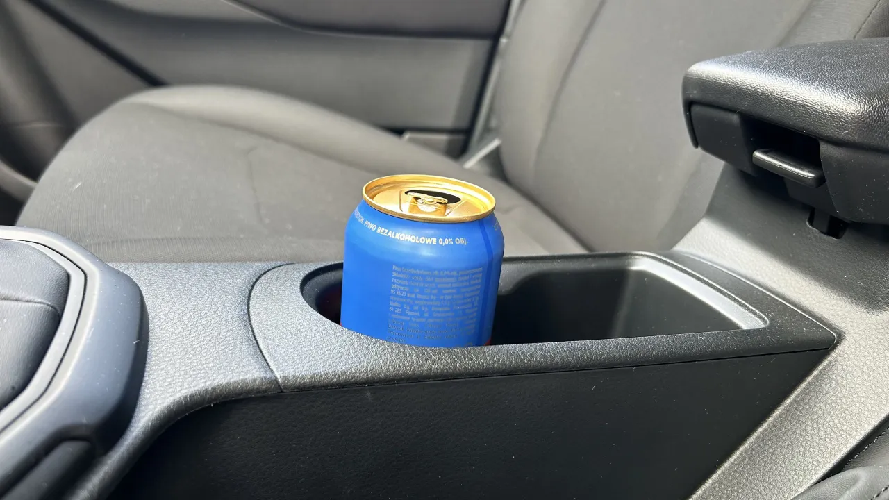 Niebieska puszka piwa bezalkoholowego 0,0% w uchwycie na kubek w samochodzie. Czy można pić piwo bezalkoholowe w miejscu publicznym? Tak, to piwo jest bezpieczne.