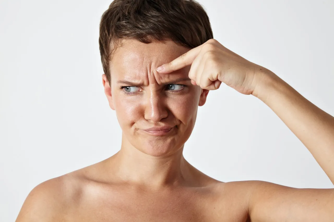 Kobieta dotykająca skóry twarzy, oznaki zmęczenia, zmarszczki