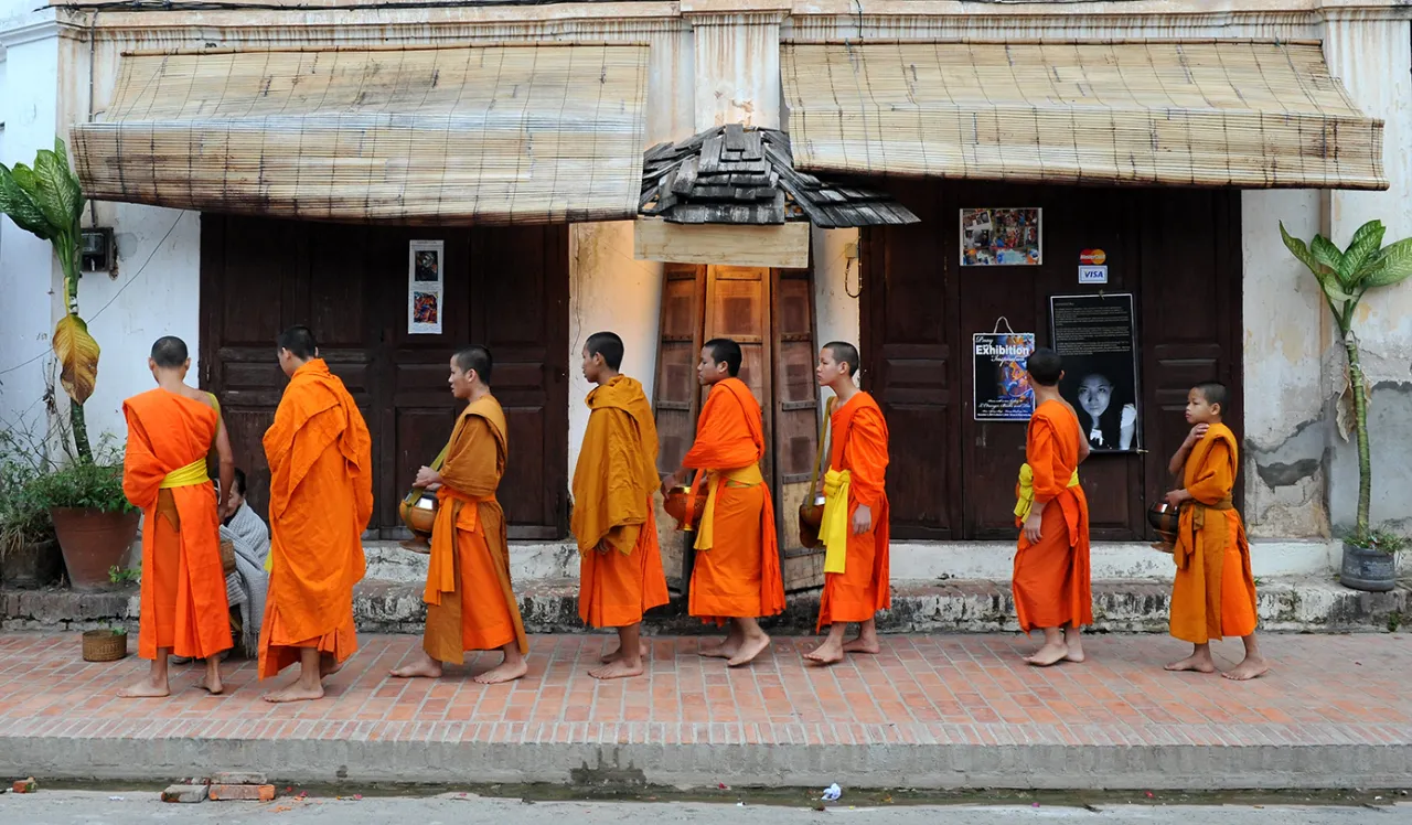Mnisi w pomarańczowych szatach idą w procesji. Czy buddyści jedzą mięso? To zależy od tradycji, ale wielu mnichów jest wegetarianami.
