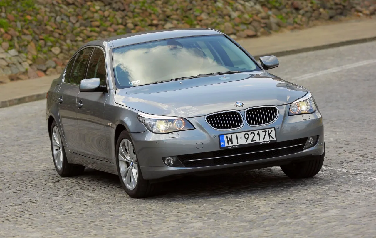 Szary sedan BMW E60 535d na brukowanej drodze.