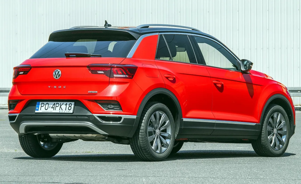 Czerwony Volkswagen T-Roc, idealny jako samoch&oacute;d dla kobiety. Stylowy, miejski SUV z czarnym dachem.