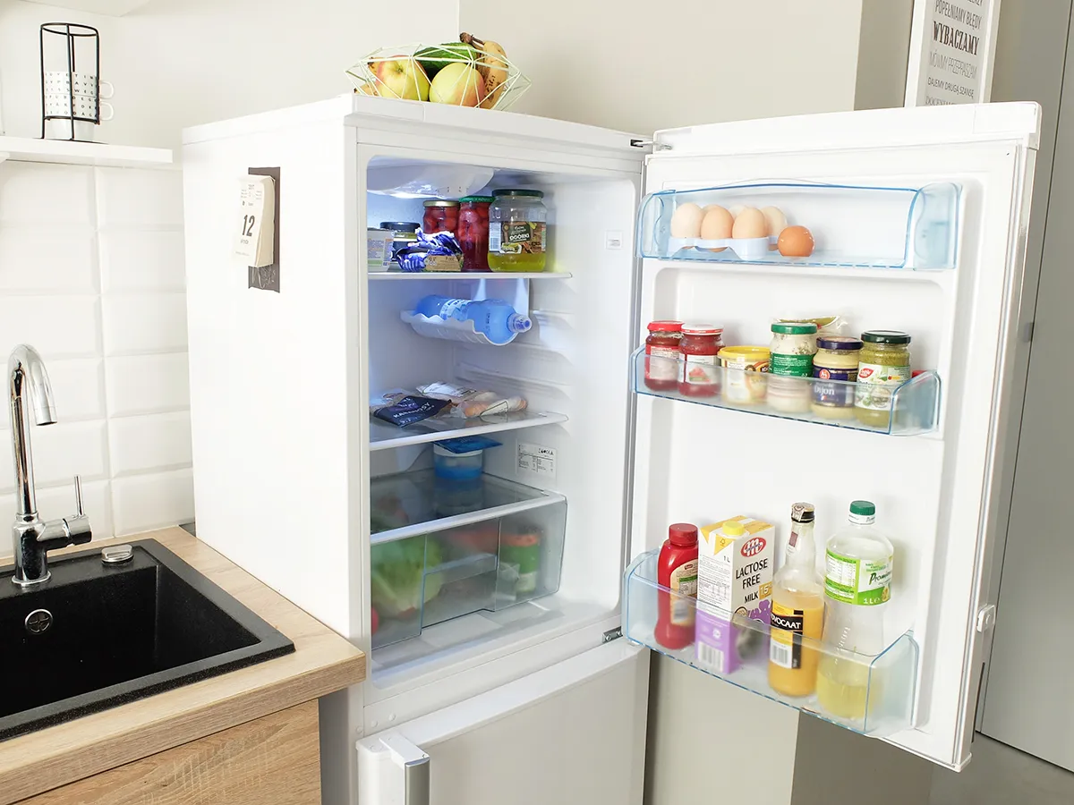 Lodówka pełna produktów, w tym jajka, słoiki i napoje. Idealne miejsce, by dowiedzieć się, jak przechowywać pierogi, by były świeże.