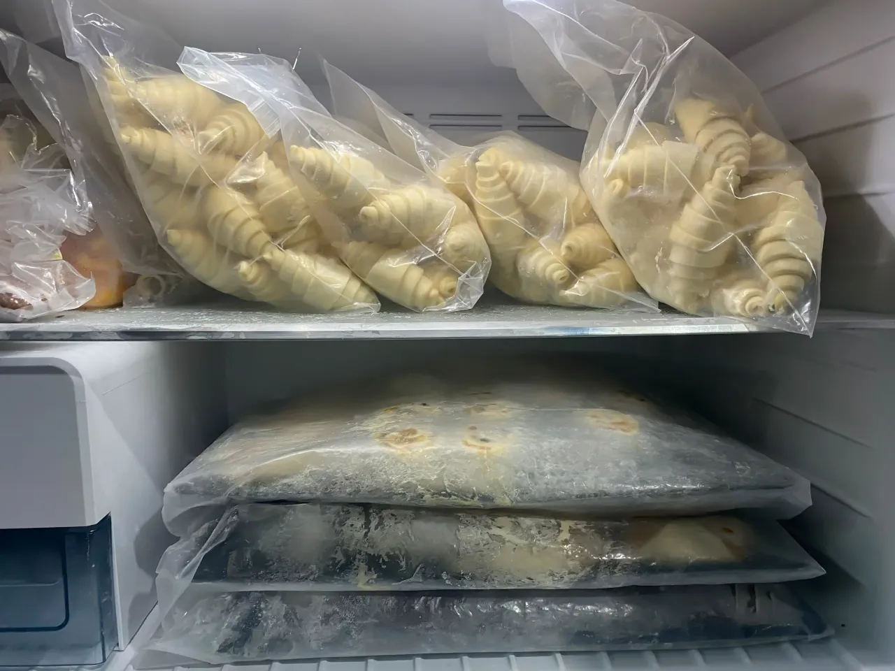 W zamrażarce piętrzą się torby z ciastami: na g&oacute;rze surowe rogaliki, na dole płaskie, zamrożone wypieki. Widać, jakie ciasta można mrozić.