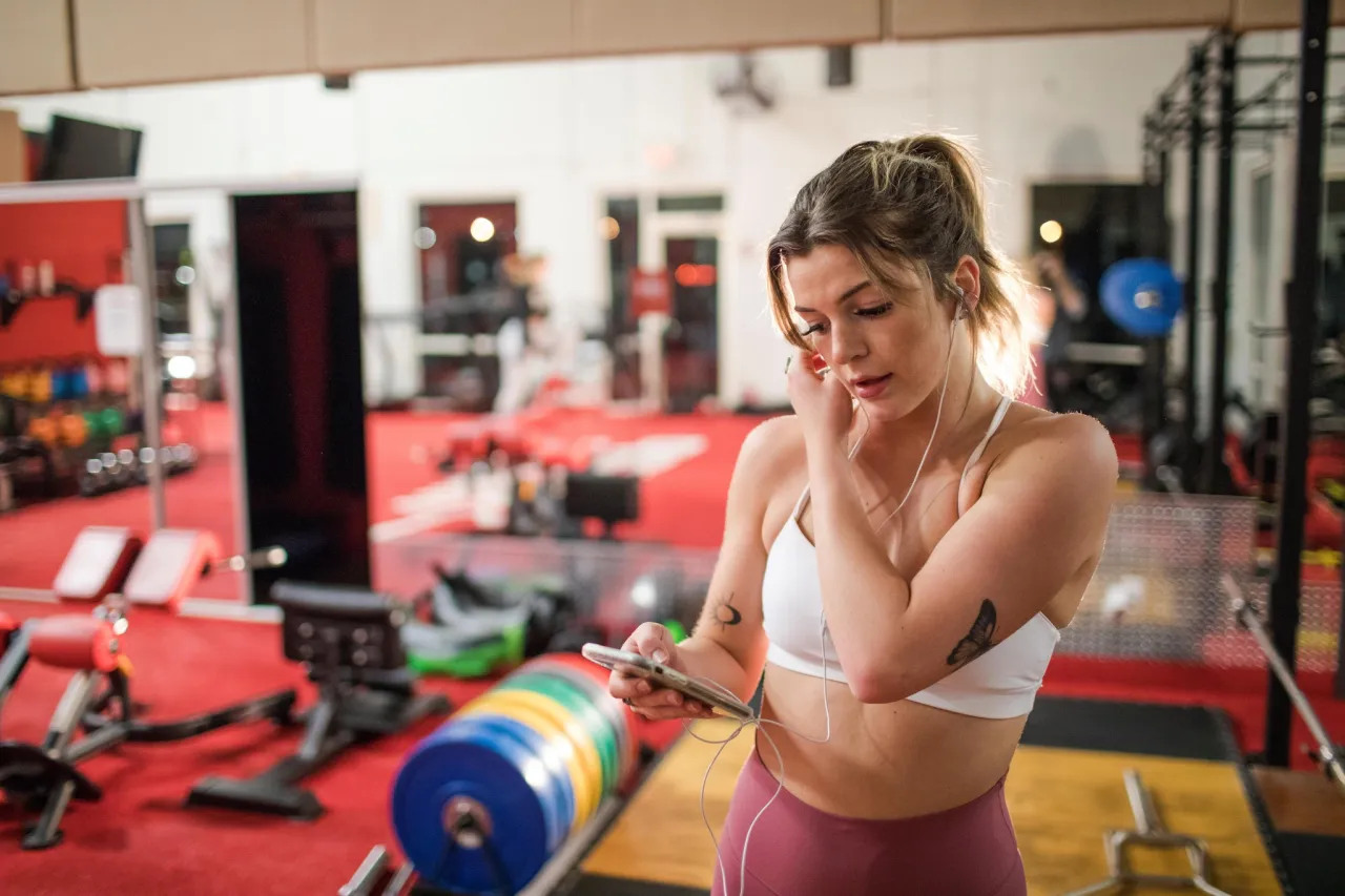 CrossFit Athletin nutzt App am Smartphone beim Training