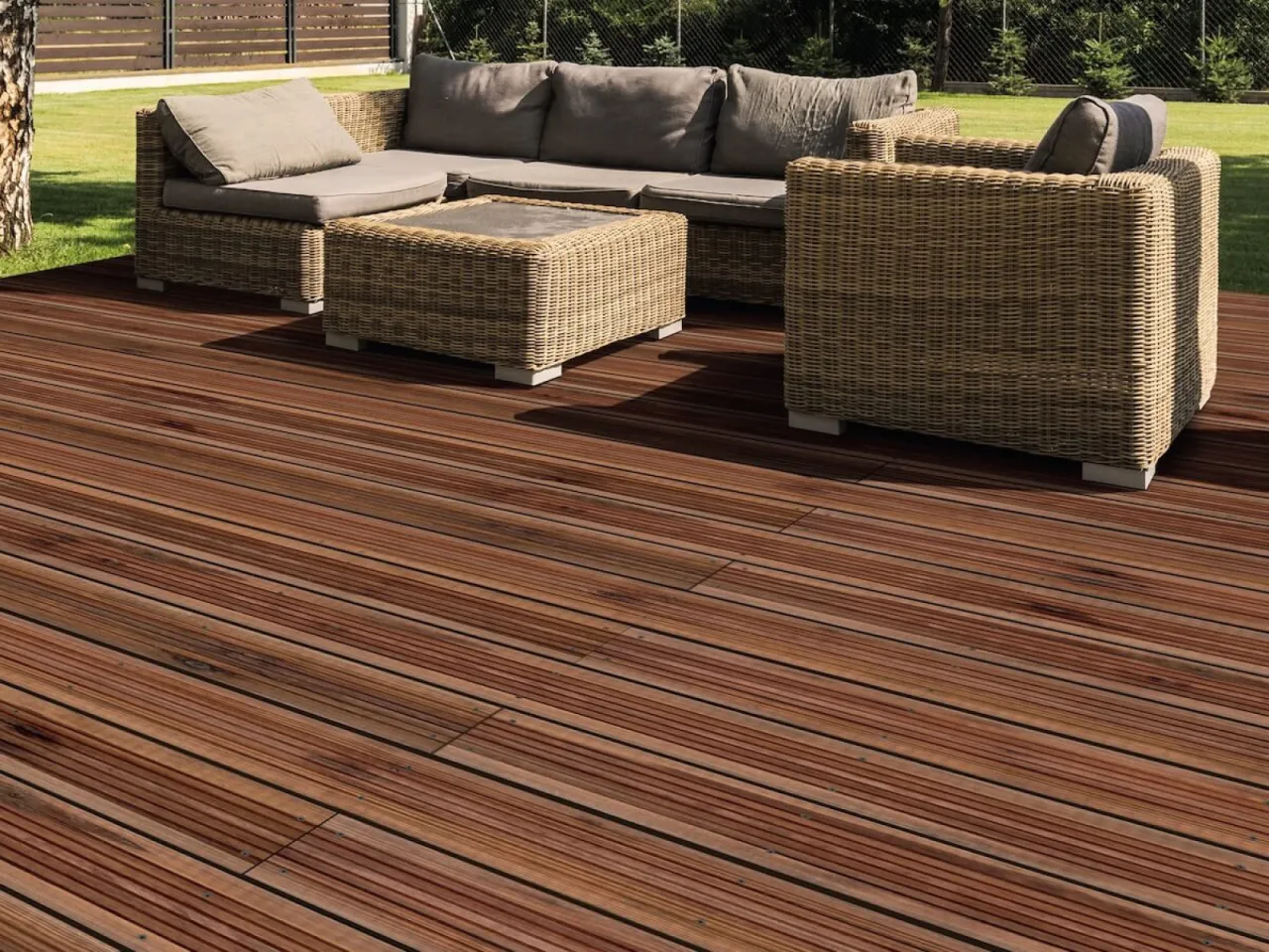 Drewniany taras z meblami rattanowymi. Zastanawiasz się, ile kosztuje budowa tarasu drewnianego?