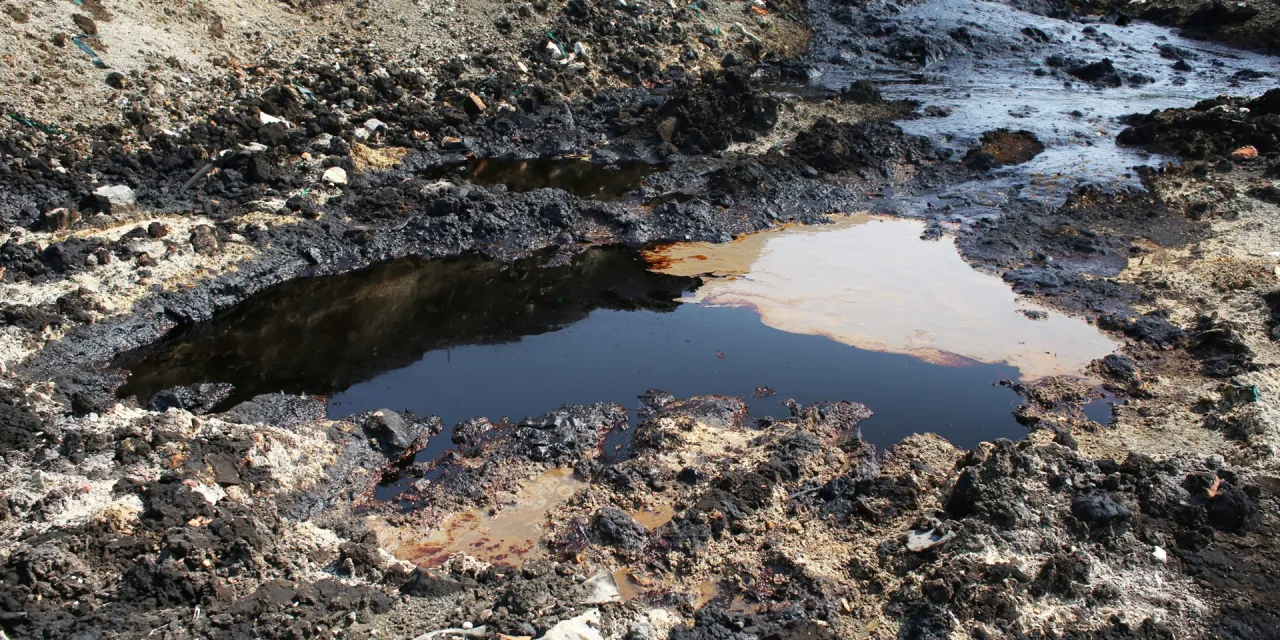 Brudna ziemia z kałużami ropy i śmieciami. Pokazuje, jak chronić glebę przed zanieczyszczeniami.