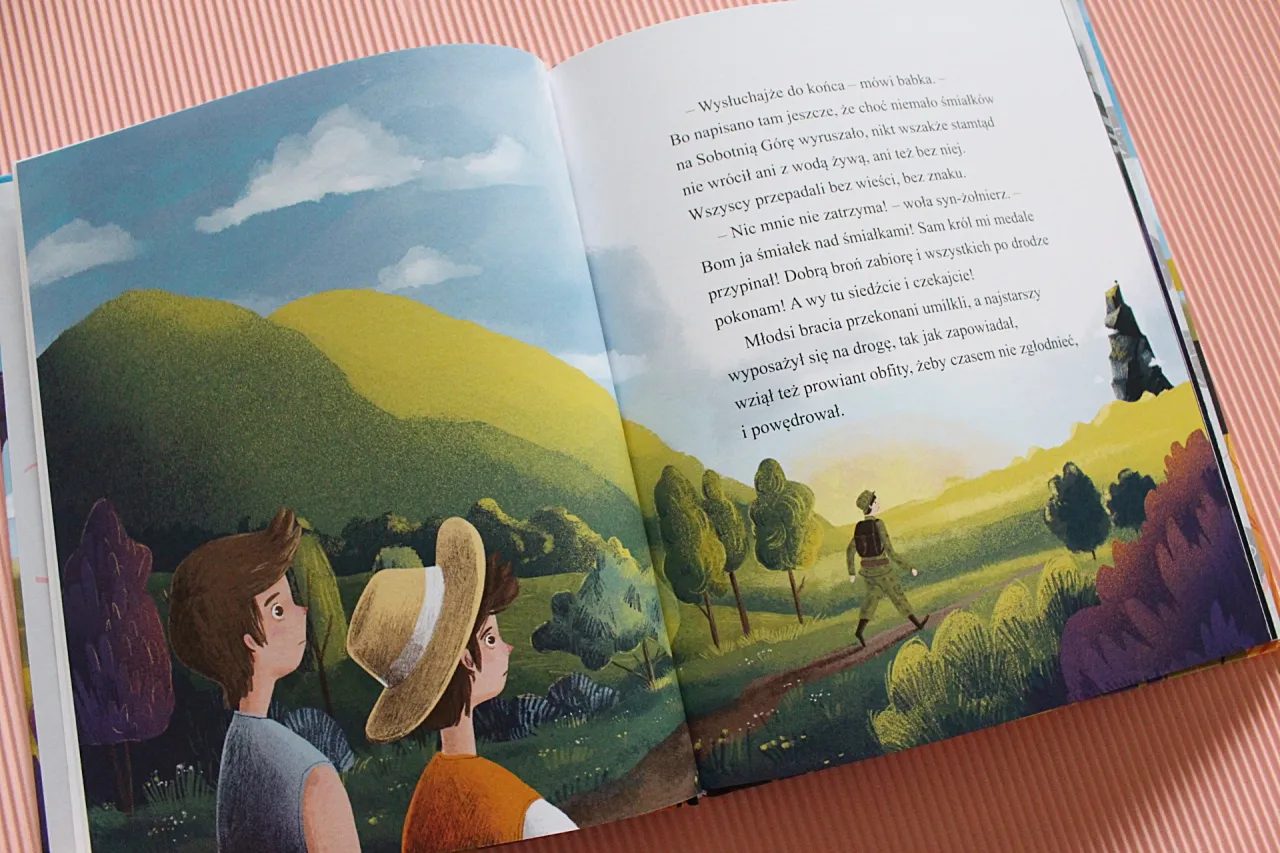 Dw&oacute;ch chłopc&oacute;w patrzy na krajobraz, gdzie samotny podr&oacute;żnik idzie ścieżką. To fragment baśni o Sobotniej G&oacute;rze.