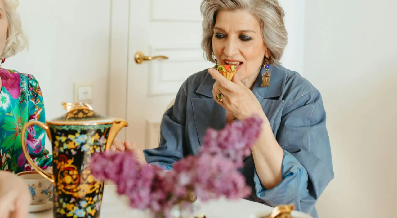 Uśmiechnięta kobieta w kuchni z ciastem i dzwoniącym telefonem