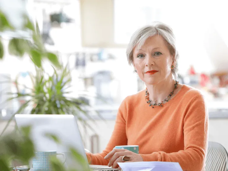 Kobieta po 50. roku życia uśmiechnięta, pewna siebie, patrząca w przyszłość