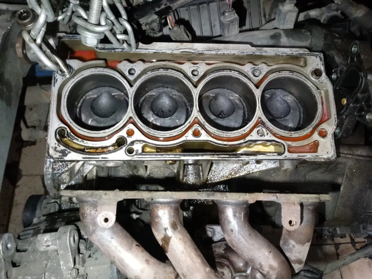 Widok na cztery cylindry silnika z widoczną uszczelką pod głowicą, która wymaga wymiany.
