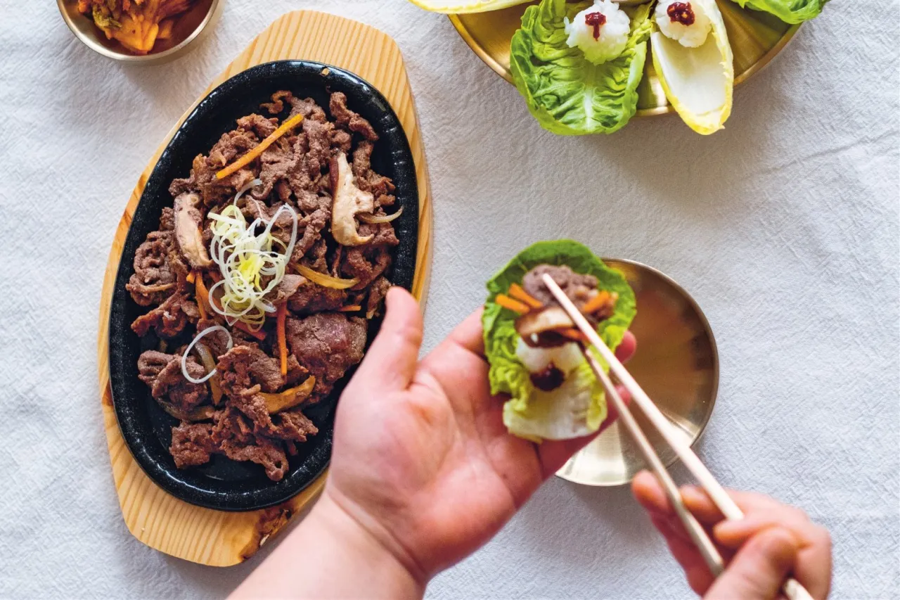 Pyszne bulgogi przepis na talerzu. Mięso z warzywami, gotowe do zawinięcia w liść sałaty.