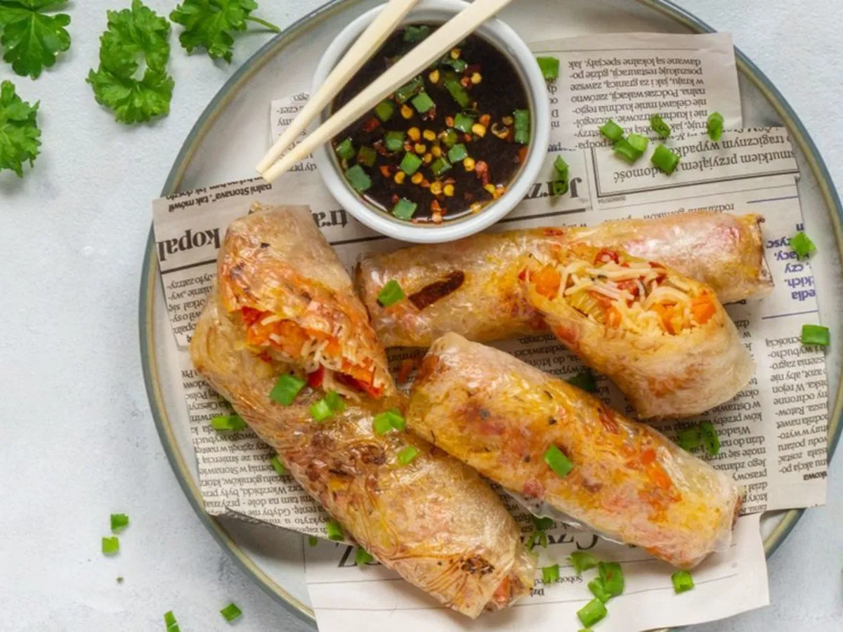 Chrupiące, pieczone sajgonki z warzywami i ryżem, podane z sosem i szczypiorkiem. Idealna przekąska.