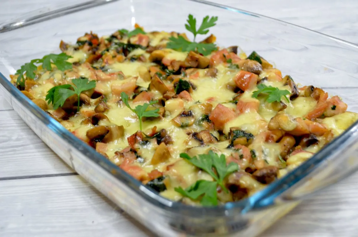 Pyszna zapiekanka z piersią kurczaka, pieczarkami i pomidorami, posypana serem. Idealna na obiad!