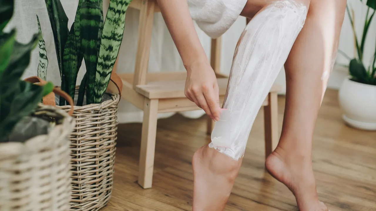 Kobieta goli nogi maszynką przed zabiegiem