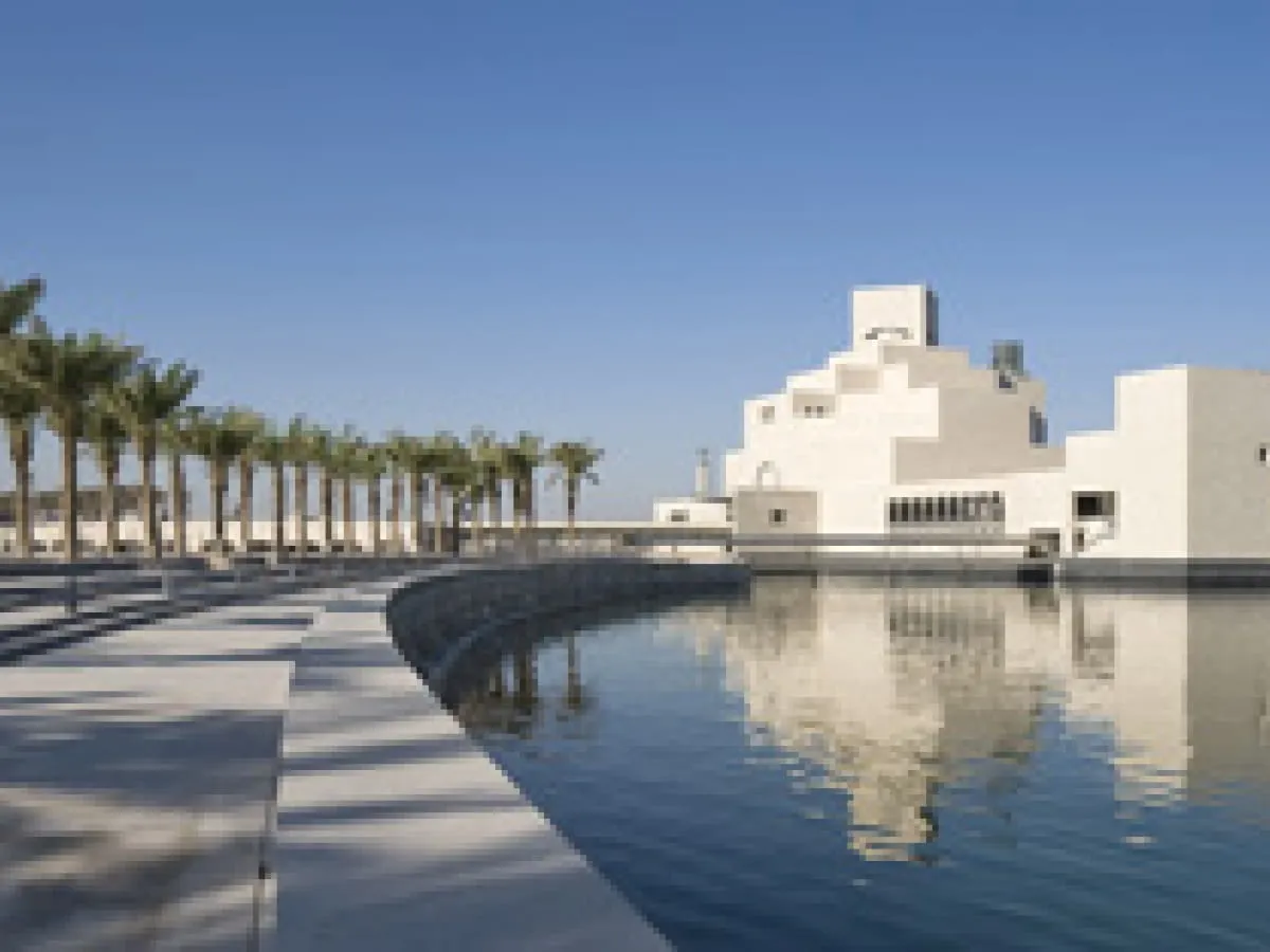 Muzeum sztuki islamskiej w Doha, z palmami i odbijającym się w wodzie budynkiem.