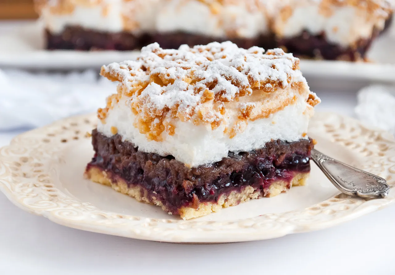 Pyszny przepis na ciasto pleśniak z dżemem porzeczkowym, posypane cukrem pudrem i kruszonką.