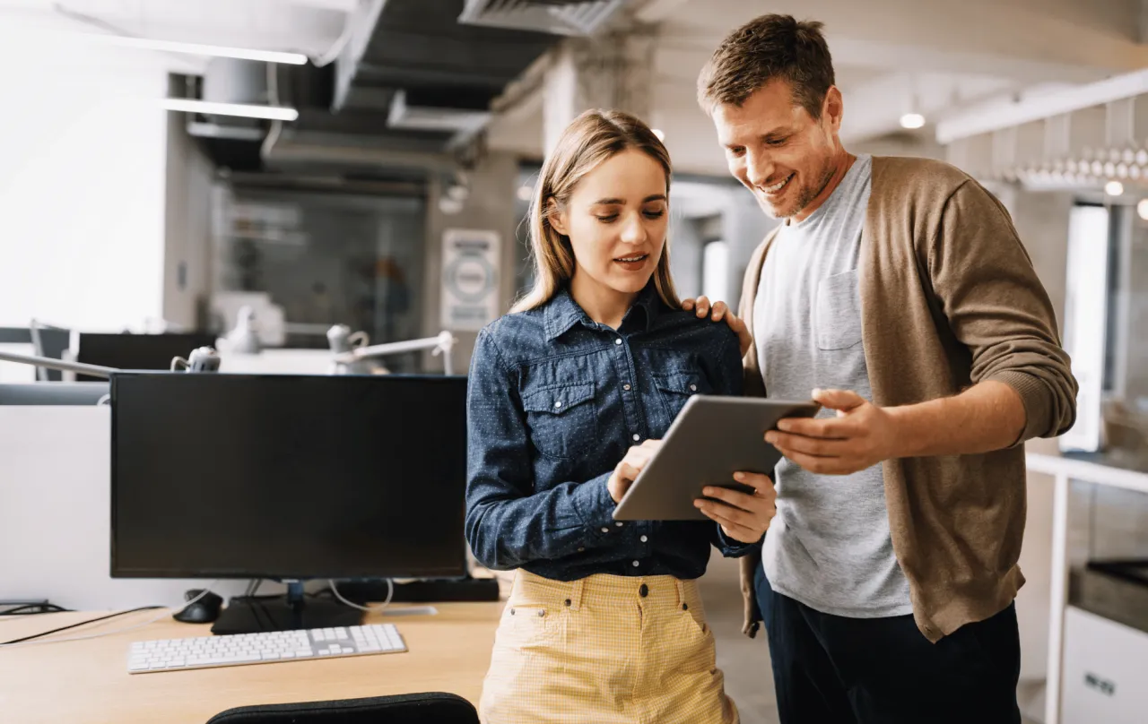 Programista i jego koleżanka analizują dane na tablecie. Może to być związane z ubezpieczeniem OC programisty.
