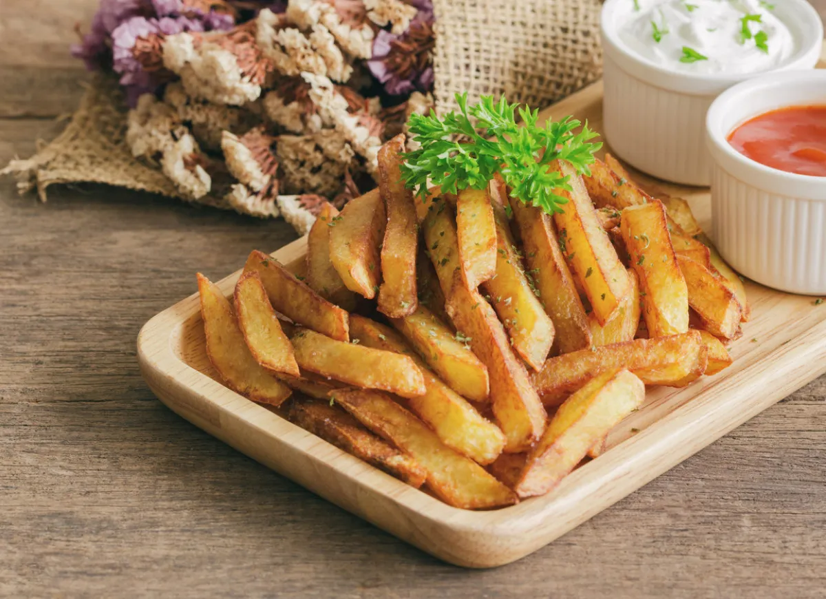 Złociste frytki z piekarnika, posypane ziołami, idealne do sosu czosnkowego i ketchup. Pytanie: czym przyprawić frytki z piekarnika?