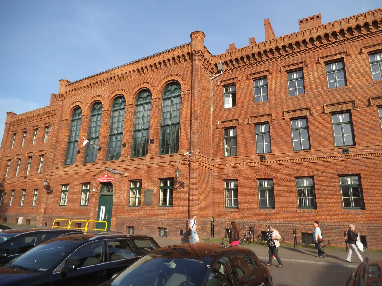 Ceglana kamienica z charakterystycznymi arkadowymi oknami. Zastanawiasz się, ile lat trwa liceum? Zazwyczaj 4 lata, ale to zależy od typu szkoły.