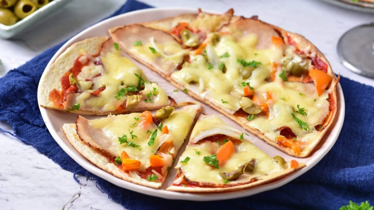 Pyszna pizza z szynką, warzywami i roztopionym serem. Posypana świeżą natką, idealna do podania z oliwkami. Warto wiedzieć, co zrobić z oregano, by nadać jej jeszcze więcej aromatu.