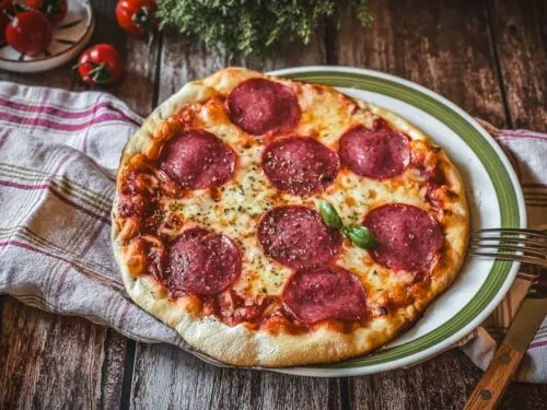 Appetitliche Pizza Salami auf einem Holztisch mit frischen Zutaten