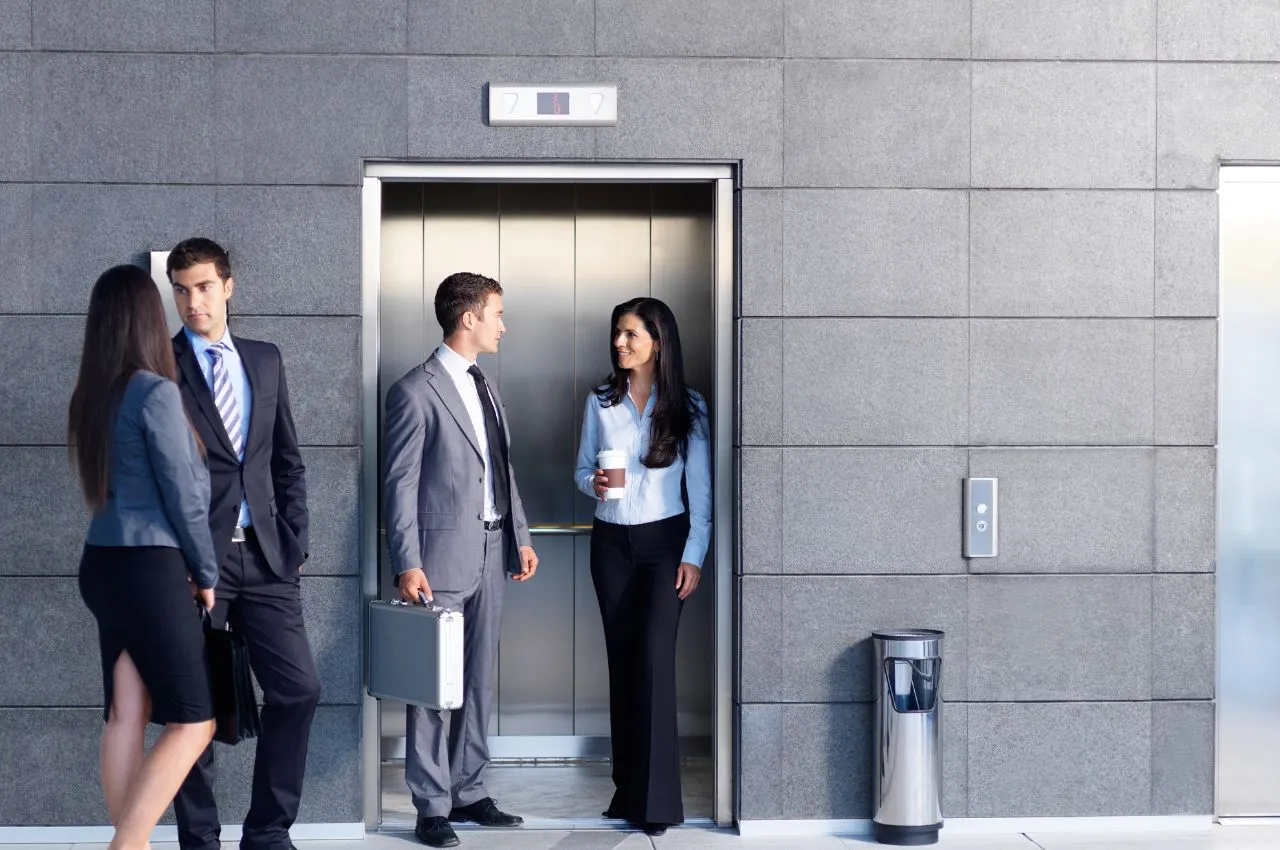 Biznesmeni czekają na windę. Zastanawiasz się, ile kosztuje wymiana windy w bloku?