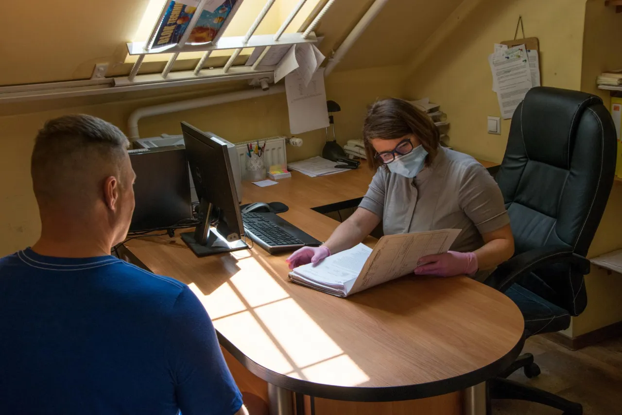 Kobieta w maseczce i rękawiczkach pokazuje mężczyźnie dokumenty, jak sprawdzić termin rozprawy rozwodowej.