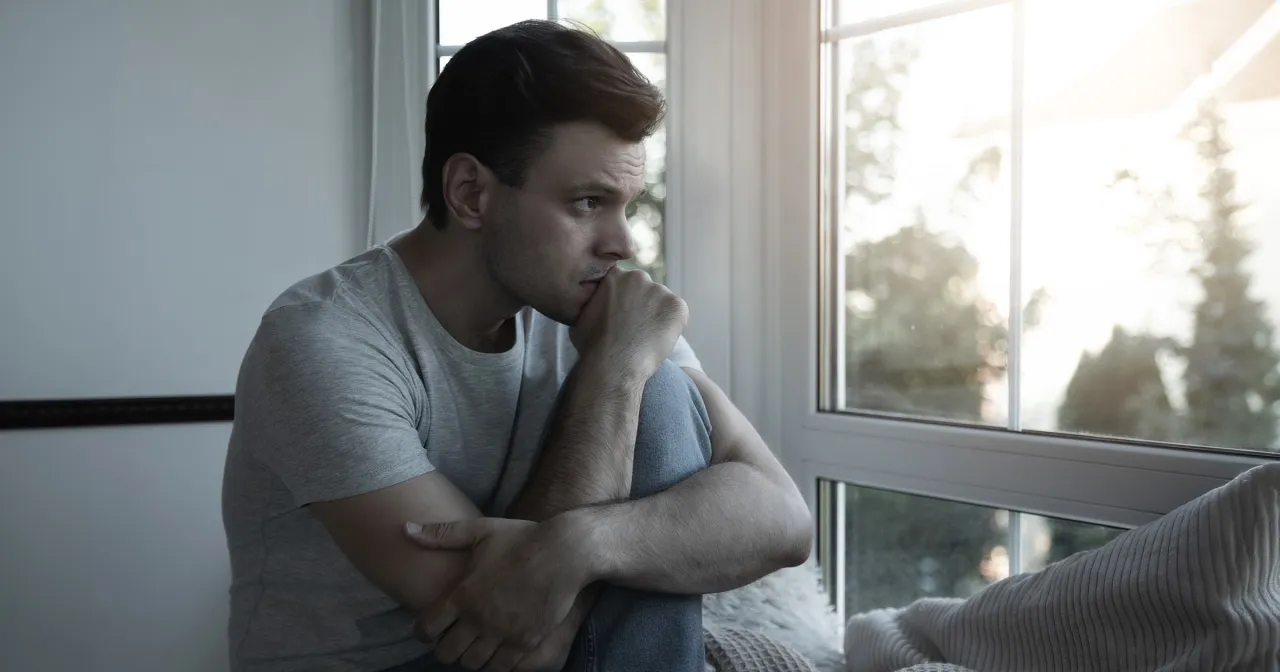 Osoba z głową w dłoniach, zamyślona nad swoimi problemami