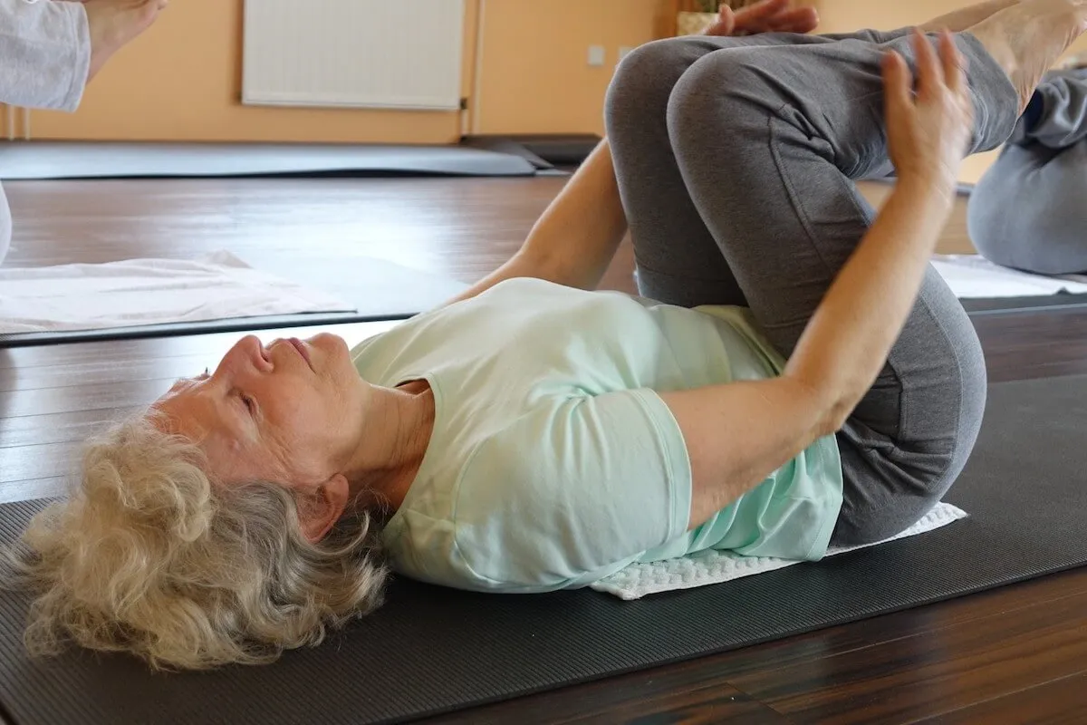 Kobieta po 50. roku życia ćwicząca jogę w domu, spokojna, zrelaksowana