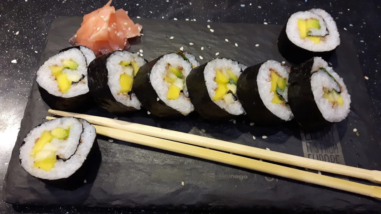 Słodkie sushi z mango i awokado, podane z imbirem na czarnej desce.