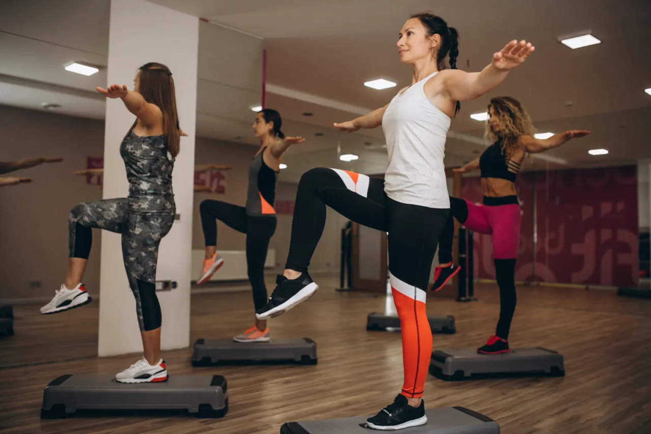 Kobiety na stepach wykonują trening aerobowy co to jest, ćwicząc r&oacute;wnowagę i kondycję.