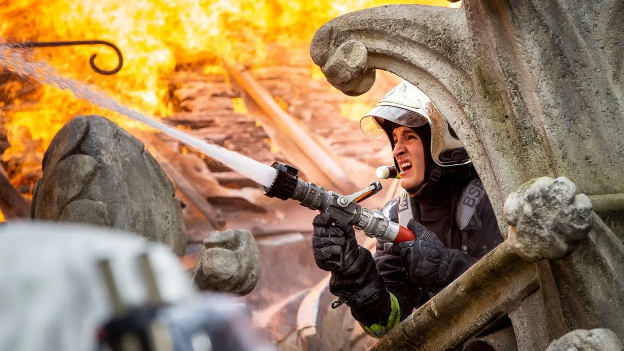 Strażak walczy z ogniem, gdy notre-dame płonie. Seanse ratownicze trwają.