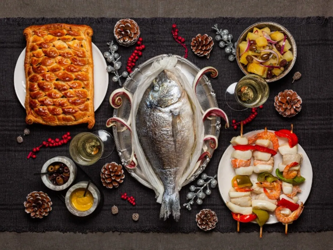 Elegancka kolacja wigilijna: pieczona ryba, pasztecik, szaszłyki z owocami morza, sałatka i dodatki. Idealne inspiracje, co ugotować na Wigilię.
