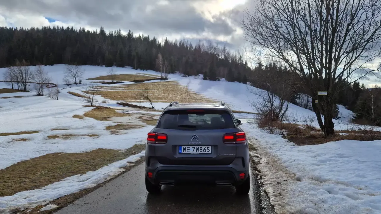 Szary Citro&euml;n C5 Aircross na drodze wśr&oacute;d ośnieżonych p&oacute;l i lasu. Dobra wartość rezydualna tego modelu to atut dla kupujących.