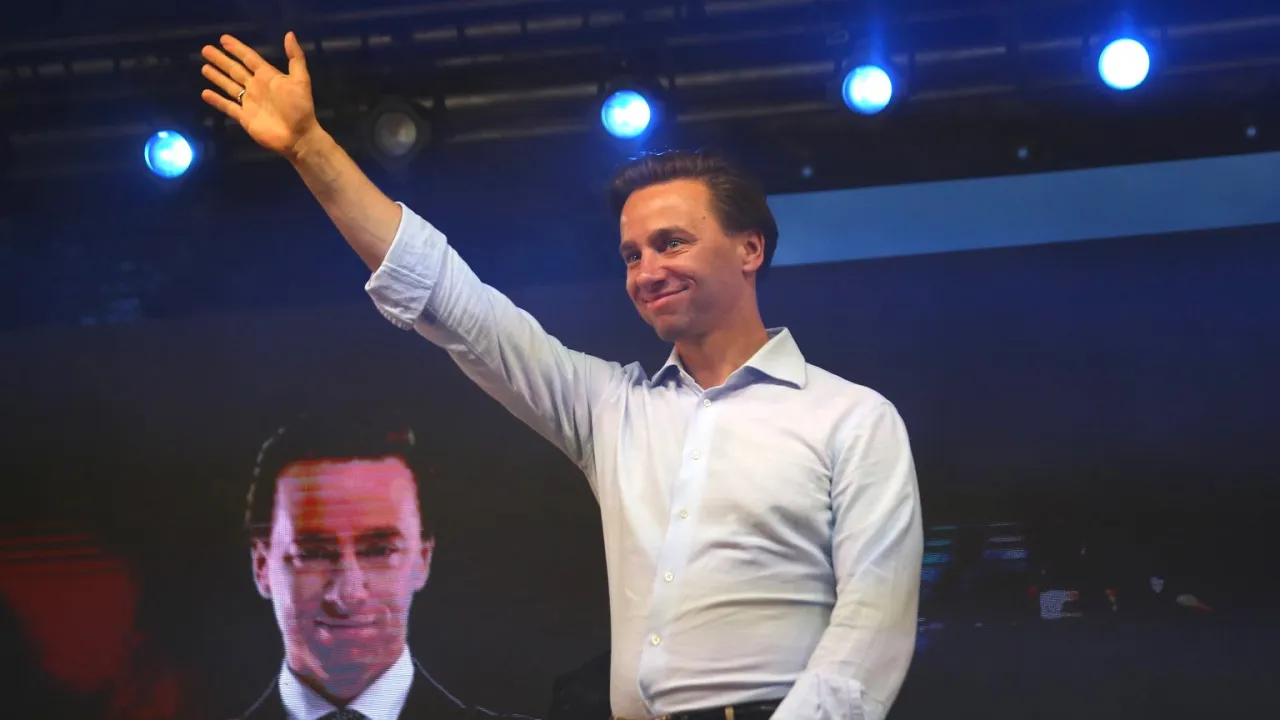 Mężczyzna w jasnej koszuli pozdrawia tłum. Na ekranie za nim widać twarz polityka. Ciekawe, ile lat ma Bosak?