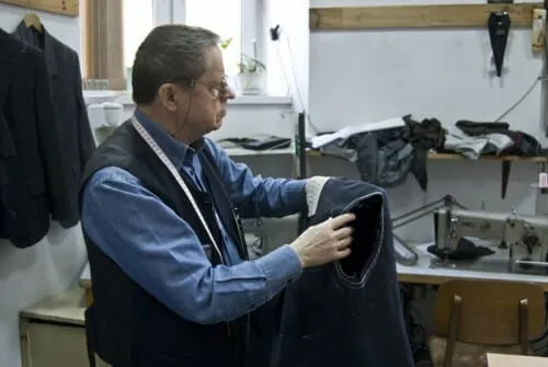 krawiec pobierający miarę ze spodni w zakładzie krawieckim