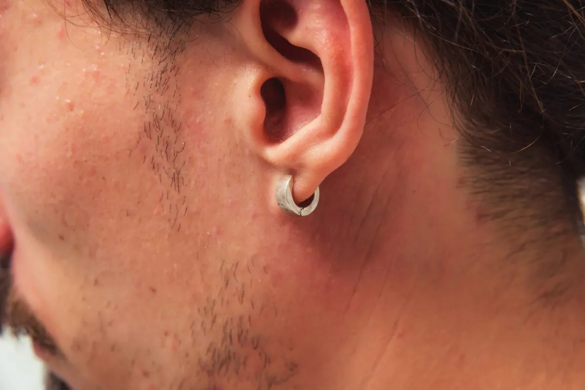 Mężczyzna z kolczykiem w uchu, nowoczesne męskie kolczyki, r&oacute;żne style kolczyk&oacute;w męskich