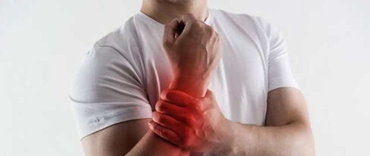 Mężczyzna trzyma się za nadgarstek, który jest zaczerwieniony, co sugeruje zespół cieśni nadgarstka.