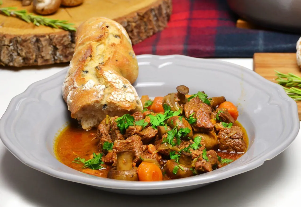 Wołowina po burgundzku z pieczarkami i marchewką, podana z chrupiącą bagietką. Aromatyczne danie, które rozpływa się w ustach.