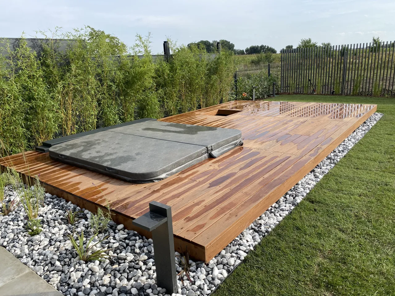 Nowoczesna aranżacja ogrodu z jacuzzi, gdzie drewniany taras tworzy idealne miejsce, by dowiedzieć się, jak zabudować jacuzzi ogrodowe.