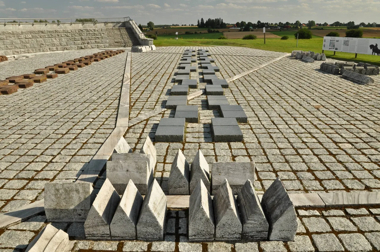 Pomnik Grunwaldu, gdzie leży Grunwald na mapie Polski, to kamienne bloki i schody na tle p&oacute;l.