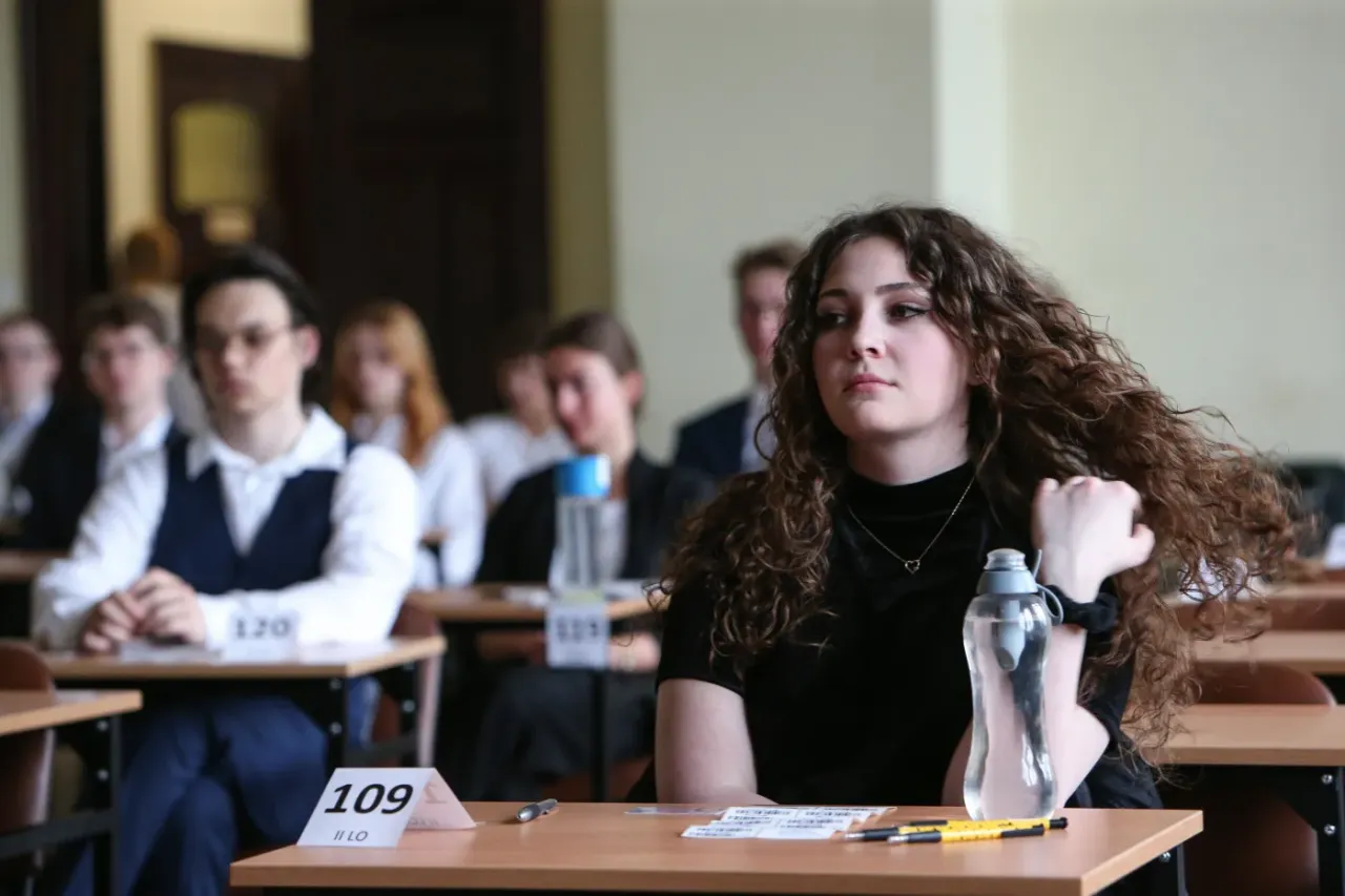 Uczniowie siedzą w sali egzaminacyjnej, zastanawiając się, ile trwa matura z polskiego.