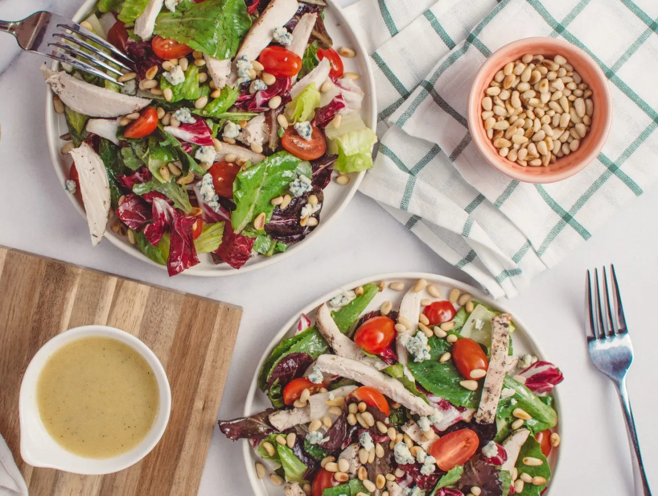 Dwie porcje sałatki z kurczakiem, pomidorkami i orzeszkami pinii. Idealny przykład, jak gotowac zdrowo i dietetycznie.