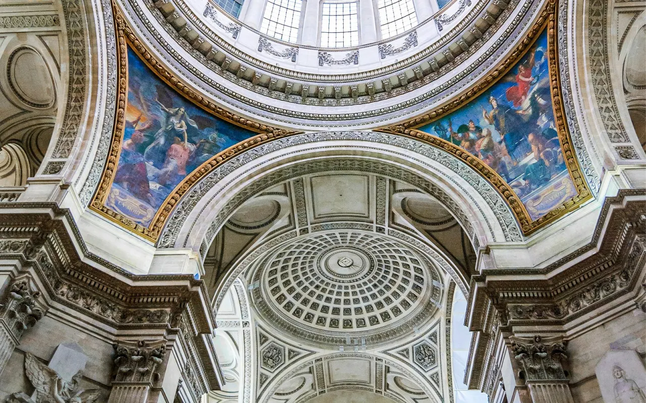 Wnętrze Panteonu w Paryżu. Monumentalna kopuła i malowidła ścienne ukazujące sceny historyczne.