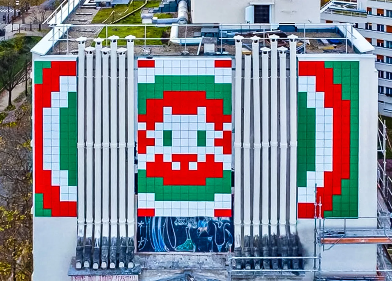 Pixelowy kosmita zdobi fasadę budynku w 13. dzielnicy Paryża. Kolorowa mozaika z czerwieni, bieli i zieleni przyciąga wzrok.